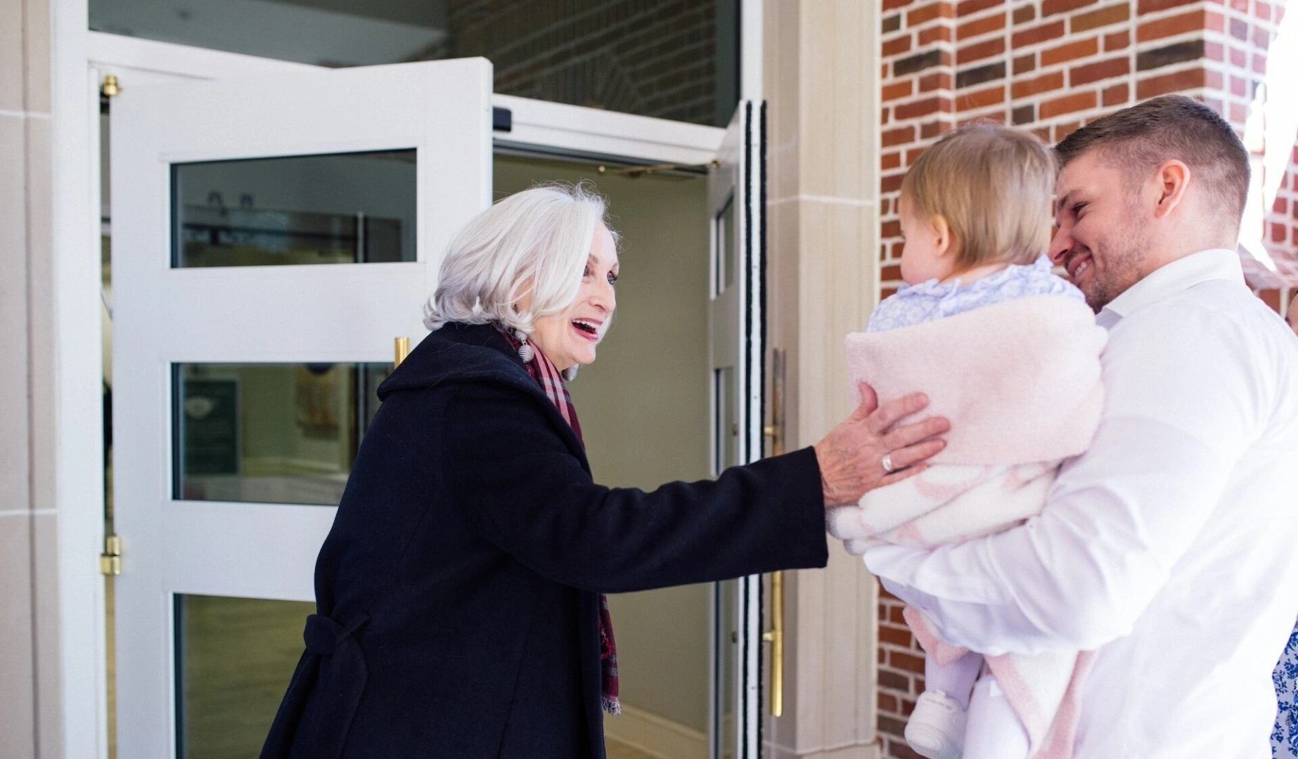 A woman welcomes a father carrying his child into their local church, inviting them to join in living and loving like Jesus.