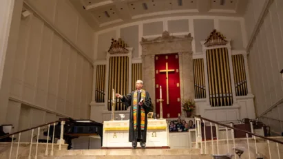 Dr. Tom Pace stands at the steps of the Sanctuary stage, giving a United Methodist Sermon inviting people to visit our church near you.